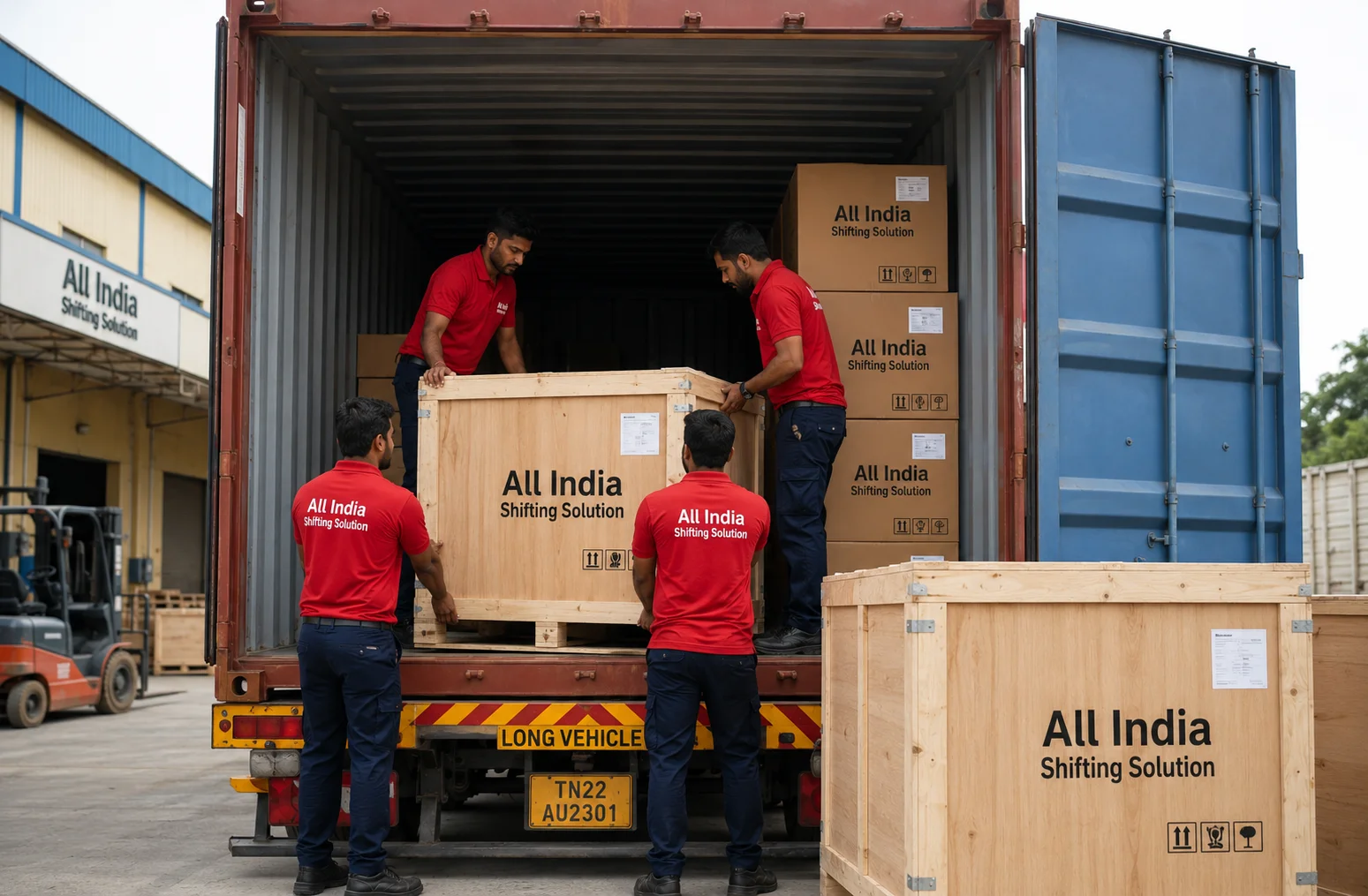 Indian movers in clean Red T-shirts with "All India Shifting Solution" in white text, dark blue trousers, and black safety shoes loading heavy export-grade wooden crates alongside corrugated cardboard boxes professionally printed with "All India Shifting Solution" in black text into a massive steel international shipping container.